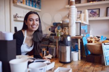 Portrait Of Smiling Female Owner Of Coffee Shop Standing Behind Counter