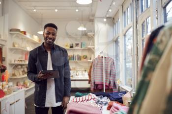 Portrait Of Male Small Business Owner Checks Stock In Shop Using Digital Tablet