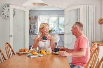 Retired Couple At Home In Kitchen Eating Breakfast Together