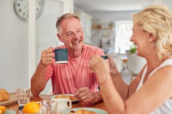 Retired Couple At Home In Kitchen Eating Breakfast Together