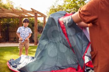 Asian Mother With Son In Garden At Home Putting Up Tent For Camping Trip Together