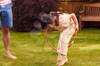 Asian Father And Daughter Having Fun Playing With Hula Hoop In Garden At Home