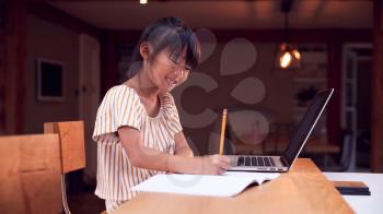 Young Asian Girl Home Schooling Working At Table Using Laptop