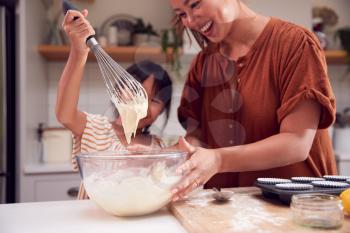 Asian Mother And Daughter Making Cupcakes In Kitchen At Home Together