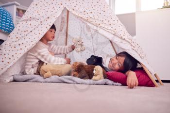 Asian Children In Tent Having Fun Playing With Toys In Bedroom Together