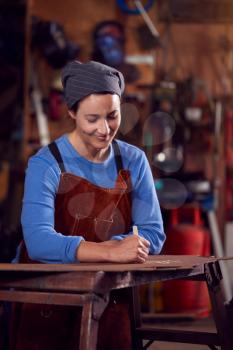 Female Blacksmith Wearing Headscarf Working On Design In Forge