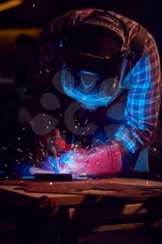 Male Blacksmith Wearing Protective Safety Visor Arc Welding Metalwork In Forge