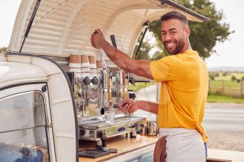 Portrait Of Man Running Independent Mobile Coffee Shop Preparing Drink Standing Outdoors Next To Van