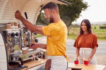 Couple Running Independent Mobile Coffee Shop Preparing Drink Standing Outdoors Next To Van