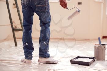 Close Up Of Man With Paint Roller Decorating New Home