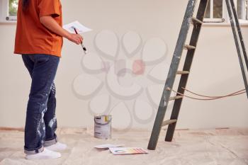 Close Up Of Woman Painting Test Squares On Wall As She Decorates Room In New Home