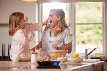 Mother And Daughter Making Messy Pancakes In Kitchen At Home Together