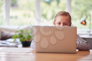 Girl Sitting At Table With Laptop Home Schooling During Health Pandemic