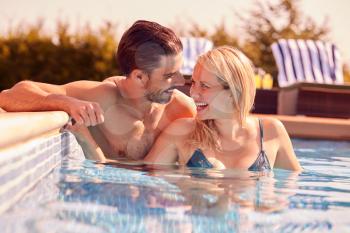 Couple Having Fun On Summer Vacation Relaxing In Outdoor Swimming Pool