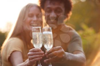 Portrait Of Mature Couple Celebrating Outdoors With Champagne Against Flaring Evening Sun