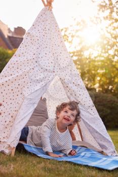 Young Boy Having Fun Inside Tent Or Tepee Pitched In Garden