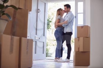 Loving Couple Kissing In Doorway As They Move Into New Home Together