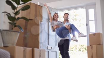 Man Carrying Woman Over Threshold Of New Home As Couple Move In Together