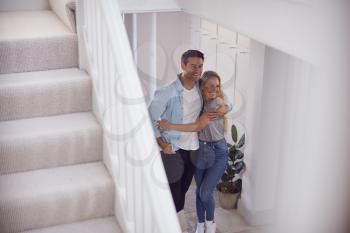 Excited Couple Standing And Hugging In Hallway Of New Home On Moving Day