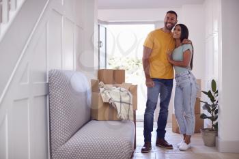 Excited Couple With Boxes Standing n Hallway Of New Home On Moving Day