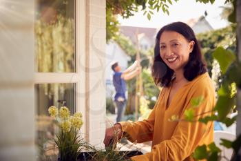 Portrait Of Mature Asian Woman Planting Plants Into Wooden Garden Planter At Home