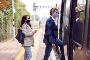Two Business Commuters Wearing Face Masks Boarding Train At Platform During Pandemic