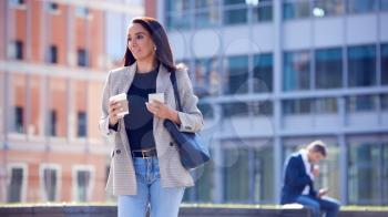 Businesswoman With Takeaway Coffee Walking To Office Holding Mobile Phone