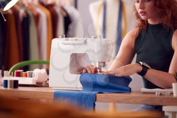 Close Up Of Female Student Or Business Owner Working In Fashion Using Sewing Machine In Studio