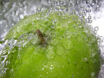 Water splashing onto a green apple