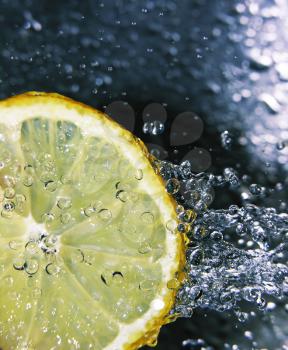 Water splashing onto a lemon - focus is on the water drops