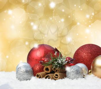 Christmas baubles in snow on gold background