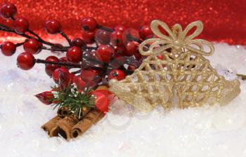 Christmas background with berries, cinammon and bells nested in snow
