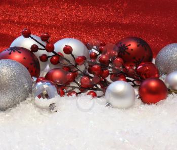 Christmas decorations nestled in snow on a glittery red background