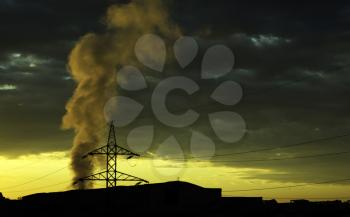 Electricity pylon and smoke from a plant in a sunrise background