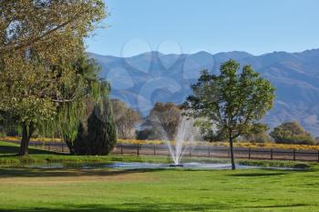 A charming decorative fountain at the golf course, against the background of distant mountains