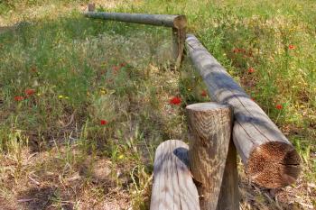 A small fence from logs on a blossoming meadow a log