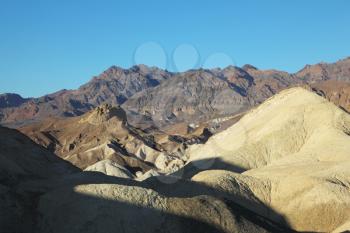 Early evening in Death Valley. Long shadows of the ancient picturesque mountains and the sky turning blue
