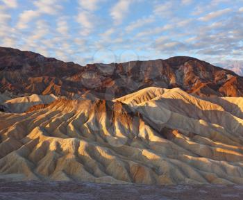 Sunset. The famous section of Death Valley in California - Zabriskie Point. Picturesque hills of pink, yellow and chocolate hues