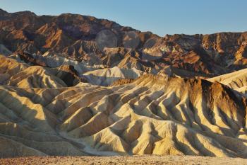 The famous section of Death Valley in California - Zabriskie Point. Picturesque hills of pink, yellow and chocolate hues at sunset
