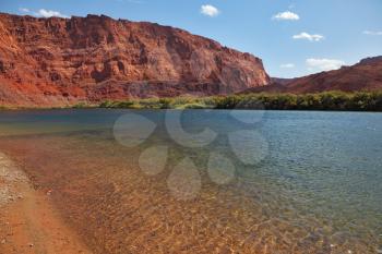 Bottling the Colorado River. Thin water ripples and a mountain of red sandstone