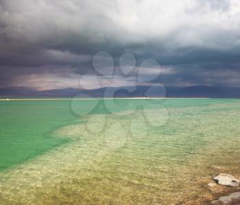 Sunset. Incredible lighting effects in a thunderstorm at the Dead Sea. Multi-colored water in the shallows
