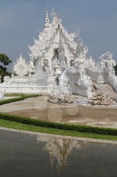 White fabulous palace in Southeast Asia. The elegant facade is reflected in a pond with live fish
