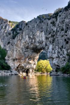 The natural stone bridge through the river in Provence and a boat with people