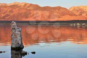 Lake stalagmites of the Tufa are reflected in smooth water of lake. Extremely beautiful landscape. Mono Lake on a sunset. 