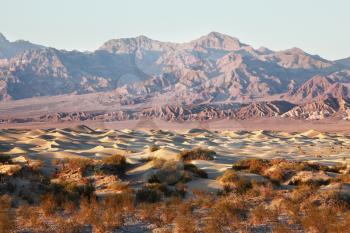 The famous Death Valley in California. Sand dunes and ancient mountains. Pink sunrise
