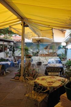 Charming rural restaurant under a linen awning. Tables are covered by the embroidered cloths
