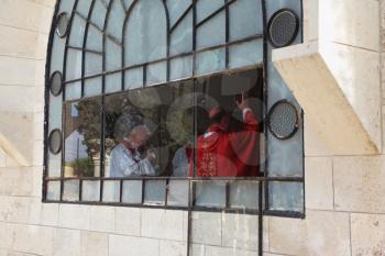 Worship in the temple. Cleric in a red mantle blesses parishioners. Jerusalem, Israel
