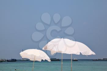 The tropical azure sea. Picturesque snow-white beach umbrellas on a sea wind
