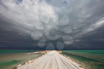 Sunset. Incredible lighting effects in a thunderstorm at the Dead Sea. The road in the middle of the sea
