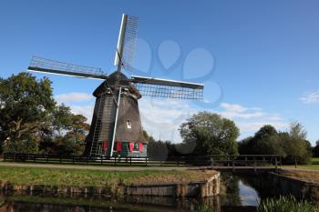 Ancient windmill on coast of a small pond. Clear autumn day in Holland